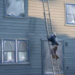 Professional painter on a ladder painting the exterior of a home during the best time for exterior painting