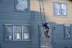 Professional painter on a ladder painting the exterior of a home during the best time for exterior painting