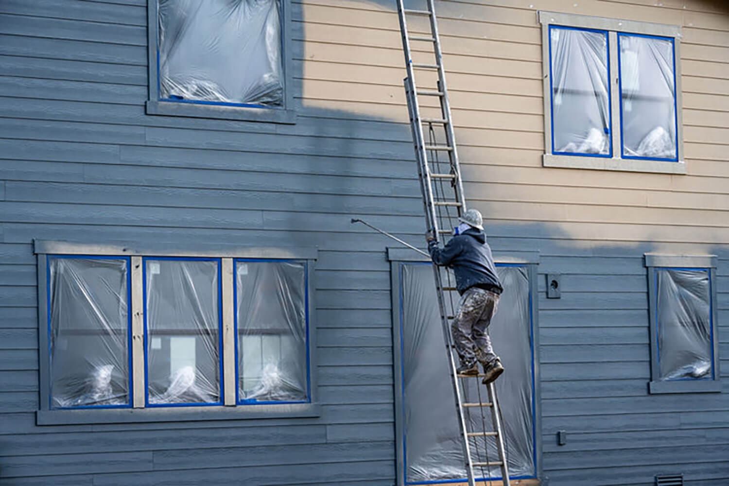 Professional painter on a ladder painting the exterior of a home during the best time for exterior painting